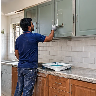 Cabinet painting service photo showing a worker repainting kitchen cabinets